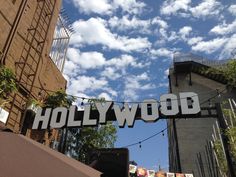 the hollywood sign is hanging on a building in front of some buildings and blue sky with white clouds