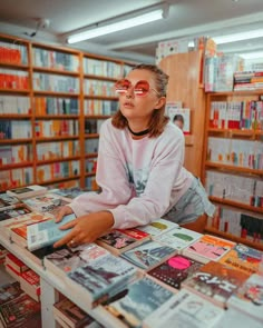 a woman sitting at a table covered in books