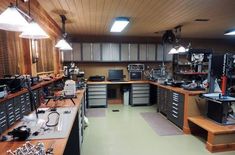 a large workbench with lots of tools on the counter and lights hanging from the ceiling