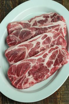 some raw meat sitting on top of a cutting board next to a knife and fork