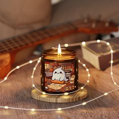 a candle that is sitting on top of a table next to some string lights and a guitar