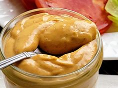 a jar filled with peanut butter sitting on top of a table next to sliced tomatoes