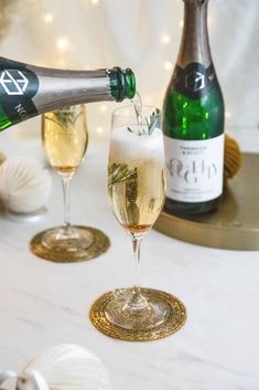 champagne being poured into two glasses on a table