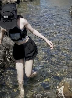 a woman wading in shallow water with a backpack on her head and wearing shorts