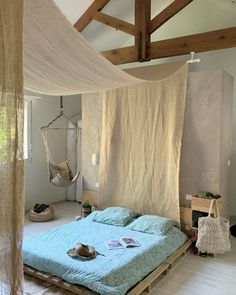 a bed sitting in a bedroom next to a wooden frame and hanging hammock