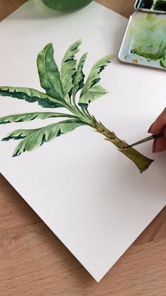 a person is painting leaves on paper with watercolors