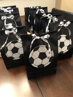 black and white paper bags with soccer balls tied to them on top of a wooden table