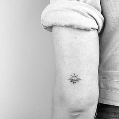 a black and white photo of a person's arm with a sun tattoo on it