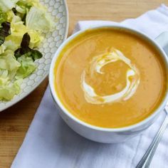 a bowl of soup next to a plate of salad