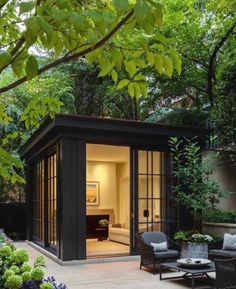 an outdoor room with chairs and tables in the middle of it, surrounded by trees