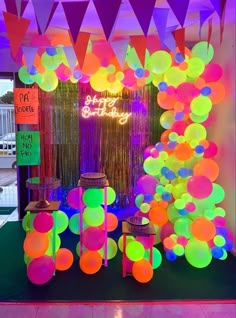 neon colored balloons and streamers are on display in front of a birthday party sign