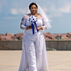 a woman dressed in white holding a blue and white bouquet