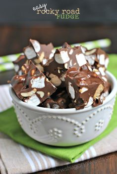 a white bowl filled with chocolate and marshmallows on top of a green napkin