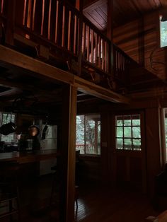 the inside of a cabin with wood floors and stairs leading to an upper level balcony