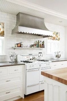 a kitchen with white cabinets and an island in front of the stove top is shown