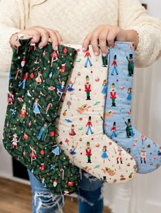 a person holding three christmas stockings in their hands