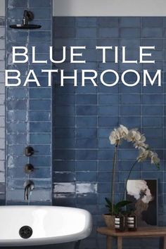 a blue tile bathroom with a white bathtub and flower in the corner on the table