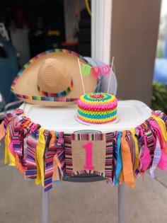 a table topped with a cake covered in colorful ribbons next to a straw hat on top of it