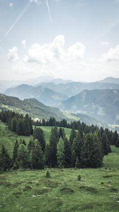 the mountains are covered in green grass and trees