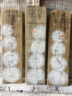 three snowmen are painted on wooden boards