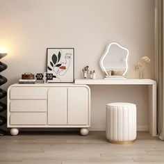 a white dresser sitting next to a mirror on top of a wooden floor in a room