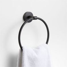 a black towel hanging on the wall next to a white toilet paper roll and a metal ring