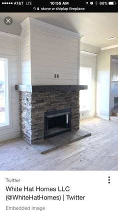 an empty living room with a stone fireplace and white painted walls, hardwood flooring