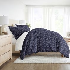 a bed with blue and white comforters in a bedroom next to a window,