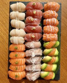 an assortment of sushi on a black tray