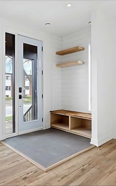 an empty room with white walls and wooden shelves on either side of the entry door