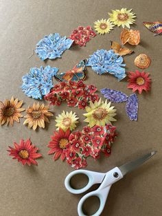 the scissors are laying on the table next to some paper flowers and butterfly pieces that have been cut out