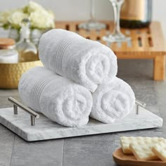 three white towels stacked on top of each other in front of a bottle of wine