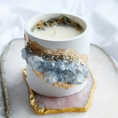 a candle is sitting on top of a small white container with gold and blue decorations