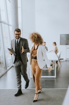 a man and woman are walking in an office