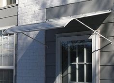 an open window on the side of a gray brick building with a white awning