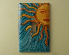 a decorative light switch plate with a sun painted on it