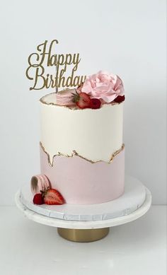 a pink and white birthday cake with strawberries on top