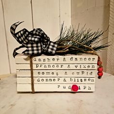 a stack of books with a ribbon tied around the top and some pine branches on top