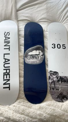 three snowboards sitting on top of a white bed next to each other, one with an image of a woman's mouth