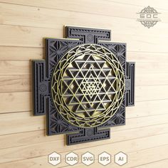 a gold and black wall hanging on the side of a wooden wall with an intricate design