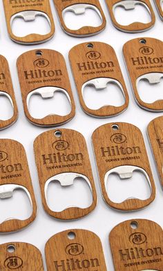 many wooden bottle openers are lined up on a table with the words hilton engraved on them