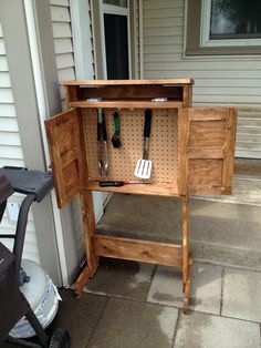 a wooden cabinet with tools hanging from it's sides on the side of a house