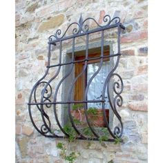 a window with iron bars on the side of a stone building and plants growing out of it