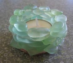 a candle that is sitting on a table next to some glass pebbles and water droplets