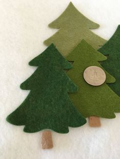 three felt christmas trees with a penny on the top one is green and the other is brown