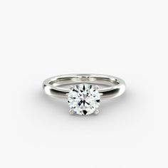 a white gold engagement ring with a round brilliant cut diamond in the center, on a plain surface