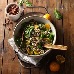 a salad with oranges, nuts and spinach in a bowl on a wooden table