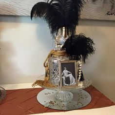 a cake decorated with feathers and an old photo is on a table in front of a wall