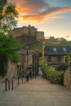 the sun is setting over an old castle like building on top of a hill with stairs leading up to it