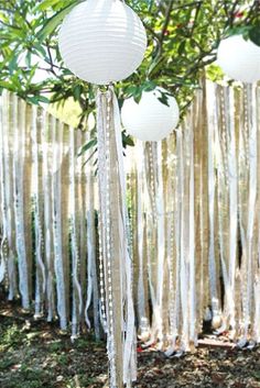 some white paper lanterns hanging from a tree